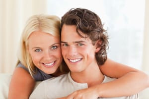 Happy young couple holding one another and smiling with beautiful white teeth